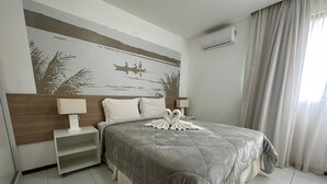 Une chambre d’hôtel avec un lit, une table de chevet, un climatiseur fixé au mur et une fenêtre avec des rideaux.