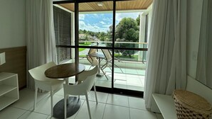 Une chambre moderne dotée d’un coin repas, d’un canapé et offrant une vue sur une piscine et la verdure environnante.