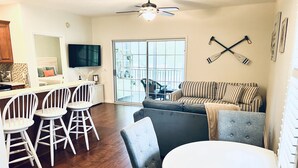 Un salon moderne avec un canapé gris, des coussins à rayures, une table à manger blanche et des chaises blanches.