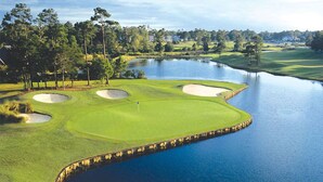 Un parcours de golf avec des bunkers de sable, un plan d’eau et des arbres environnants.