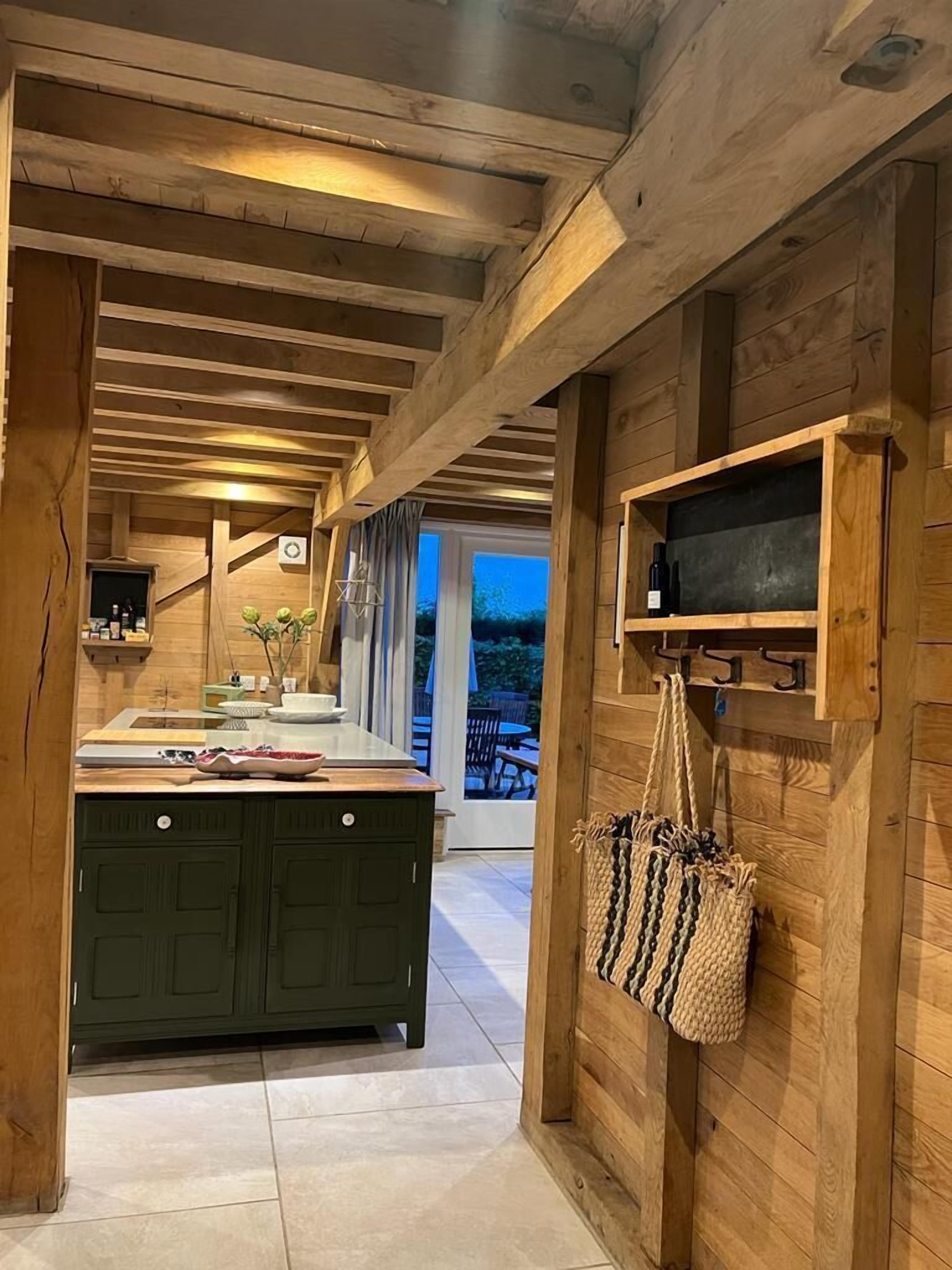 A wooden interior with a kitchen area, a hanging bag, and a shelf with bottles.