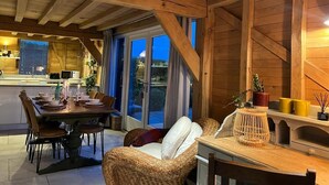 A cozy dining area with a wooden ceiling, a dining table set for four, and a wicker chair. - The Hen House (Ware)