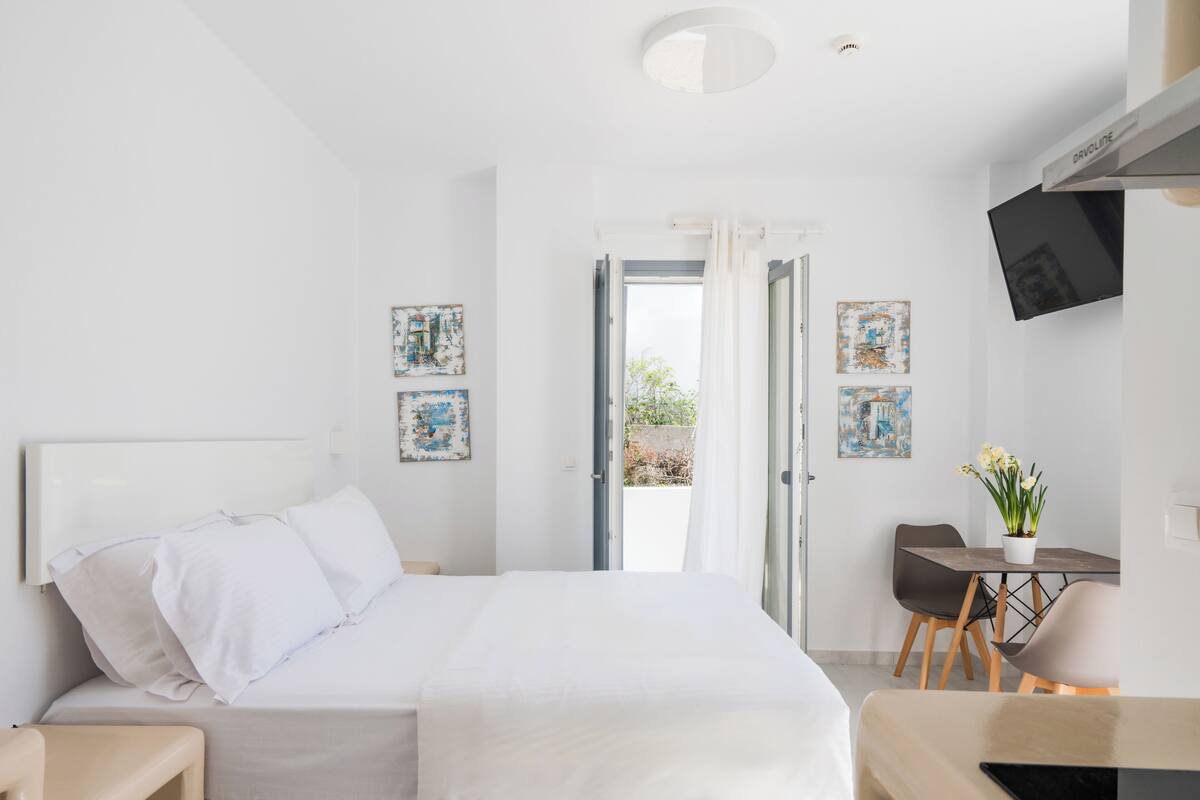 A modern hotel room with a bed, a desk, and a TV.