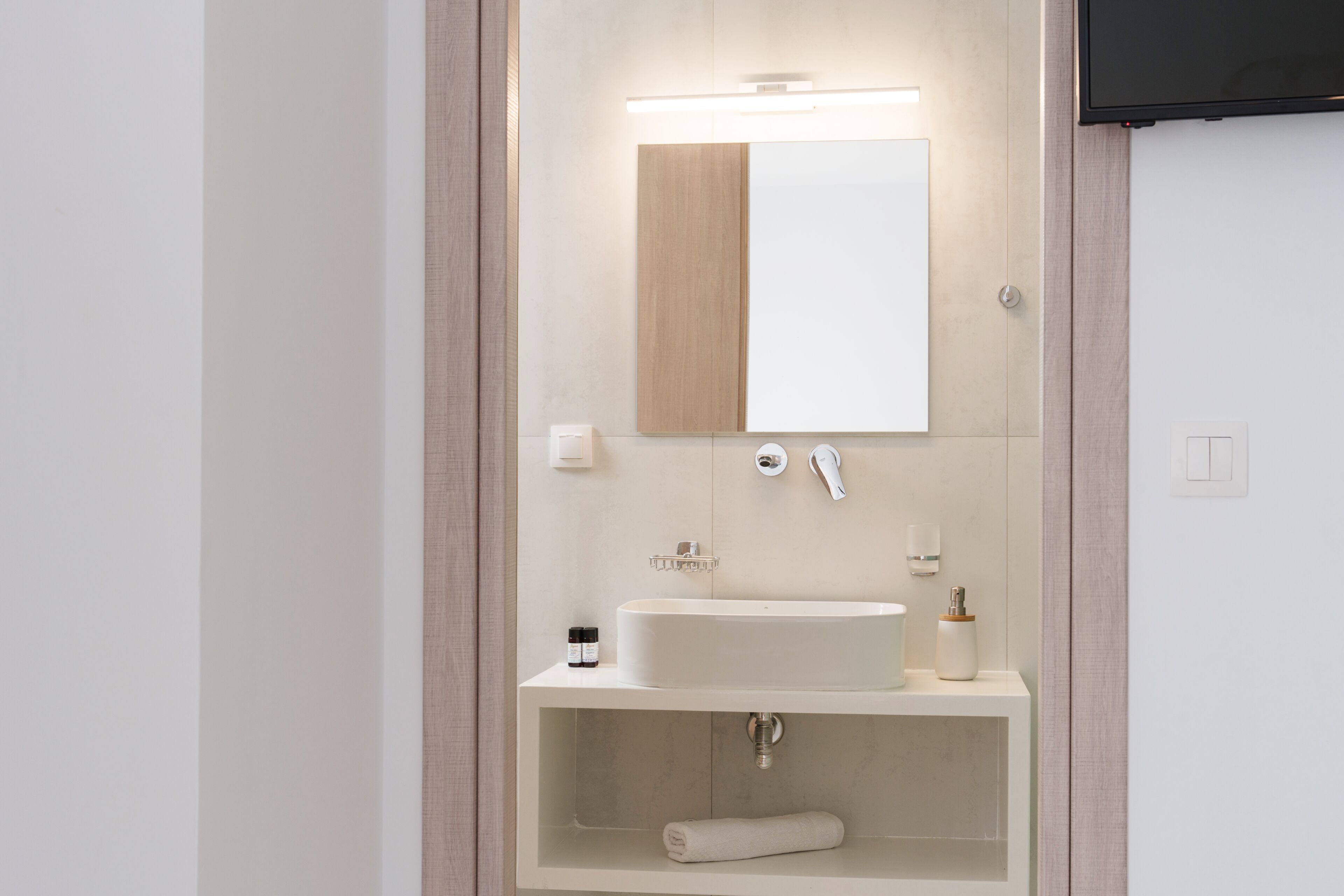 A modern bathroom with a built-in sink, mirror, and towel rack.