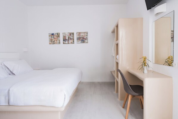 Un dormitorio moderno con una cama, un escritorio con silla, y tres cuadros abstractos en la pared.