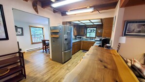 A spacious kitchen with wooden flooring, a large island, and a built-in refrigerator. - Juneau Cabin near Eaglecrest & Trails (Juneau)