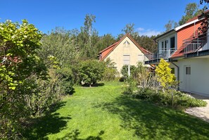 A residential property with a well-maintained lawn, a house with a red roof, and a balcony.
