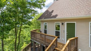 A two-story house with a wooden deck and a green door. - Bear Walk-Fire Pit - Hot Tub - Charcoal Grill (Bryson City)