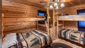 A cabin with wooden walls and floors, a bunk bed, a ceiling fan, and a window with a view. - Bear Walk-Fire Pit - Hot Tub - Charcoal Grill (Bryson City)
