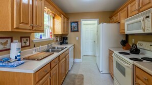 A kitchen with wooden cabinets, a white refrigerator, a microwave, a stove, and a sink. - Bear Walk-Fire Pit - Hot Tub - Charcoal Grill (Bryson City)