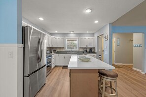 A modern kitchen with stainless steel appliances, white cabinetry, and a central island with a bowl.