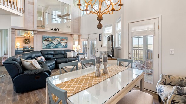 Ein geräumiges Wohnzimmer mit einer schwarzen Ledersofa, einem Glastisch und einem Chandelier.