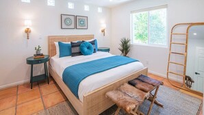 A bedroom with a bed, bedside tables, a ceiling fan, a window with a view, and a ladder. - Spacious Desert Home | Heated Pool (Scottsdale)