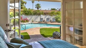 A bedroom with a view of a swimming pool, a balcony, and outdoor seating. - Spacious Desert Home | Heated Pool (Scottsdale)