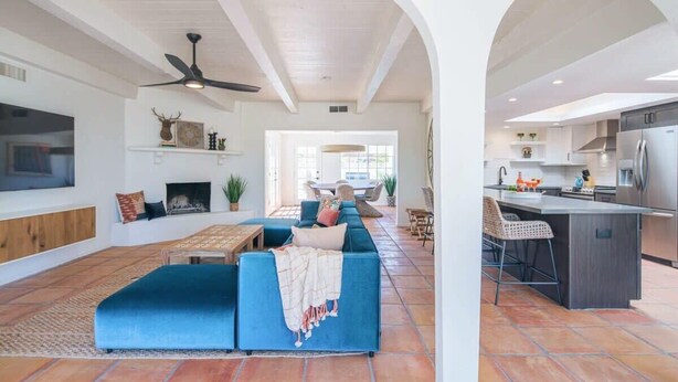 A spacious living area with a blue sofa, a fireplace, and a dining table. - Spacious Desert Home | Heated Pool (Scottsdale)