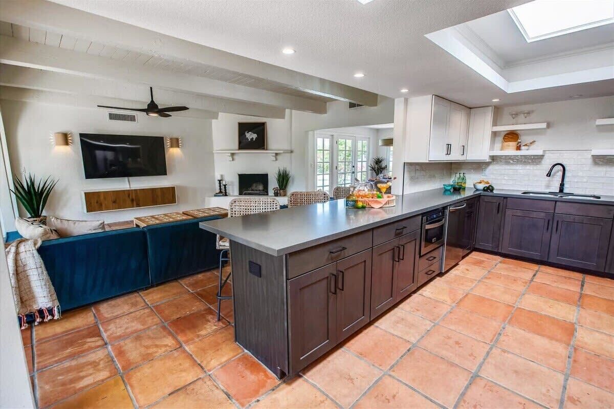 Een moderne keuken met een centraal eiland, inbouwmeubels en een zithoek met een bank.