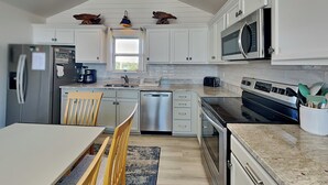 Una cucina moderna con mobili bianchi, elettrodomestici in acciaio inossidabile e un'area pranzo con tavolo e sedie.