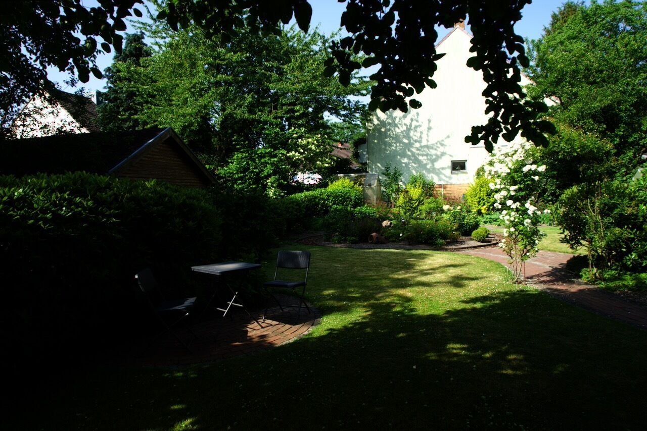 Un jardin avec une pelouse, une petite table et des chaises, et un chemin pavé de briques.