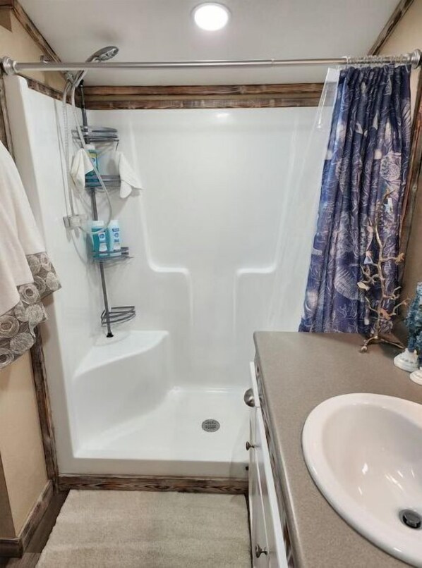 A bathroom with a shower, a sink, and a toilet.