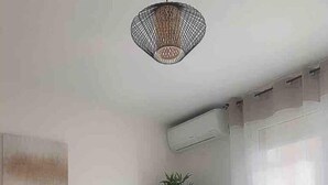 A modern room with a desk, chair, potted plant, and a hanging light fixture.