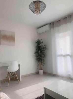 Una camera moderna con scrivania, sedia, pianta in vaso e lampadario.