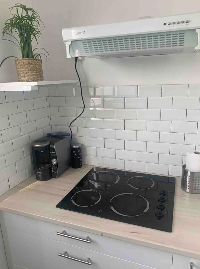 Een keuken met een inbouwfornuis, een koffiezetapparaat en een hangende plant.