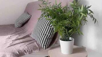 Un salon moderne avec un canapé, des coussins à motifs, une plante en pot et une œuvre d’art géométrique accrochée au mur.