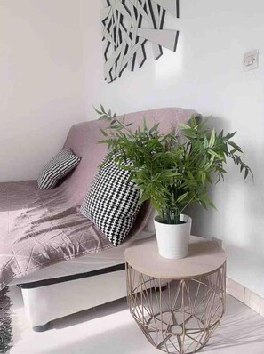 Un soggiorno moderno con un divano, cuscini decorati, una pianta in vaso e un quadro a motivi geometrici.