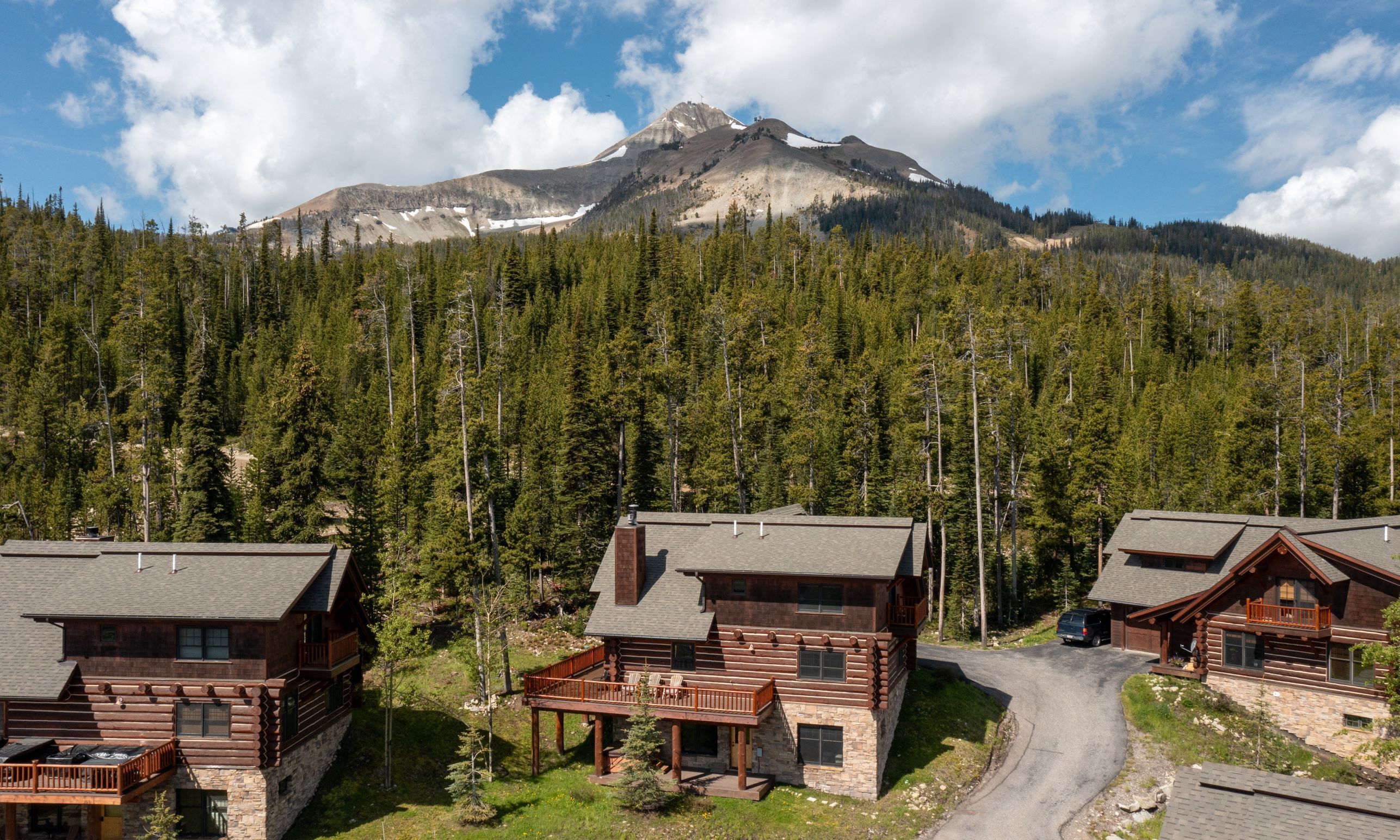 A log cabin resort with multiple cabins, a stone foundation, and a view of a mountain.