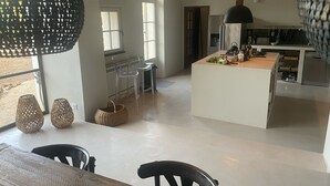 A spacious kitchen with a central island, a dining area with chairs, and a large window providing natural light. - Traumhaftes Anwesen, Dorflage, am Fuße des Mt. Ventoux (Villes-sur-Auzon)
