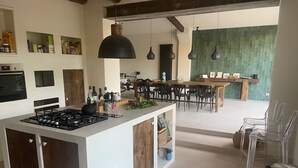A modern kitchen with a central island, wooden cabinets, and a dining area with a green accent wall. - Traumhaftes Anwesen, Dorflage, am Fuße des Mt. Ventoux (Villes-sur-Auzon)