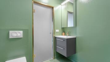 Een badkamer met een wit toilet, een wastafel met een spiegel erboven en een deur met gouden lijst.