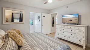 A bedroom with a bed, a ceiling fan, a TV, and a dresser. - Royal Orleans 117 - Great value, first floor w/pool (Redington Beach)