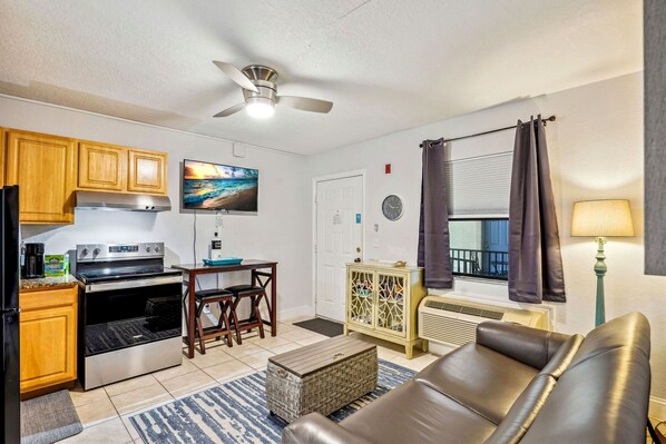 A compact living space with a kitchenette, a dining area, a seating area, and a window with curtains.