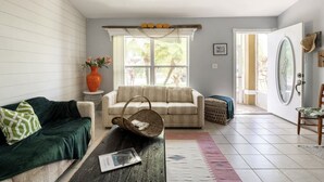 A living room with a sofa, a coffee table, a wicker basket, and a vase with flowers.