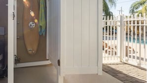A white door leading to a room with a surfboard and towels hanging on the wall.
