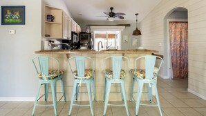 A kitchen with a central island, bar stools, and a ceiling fan.