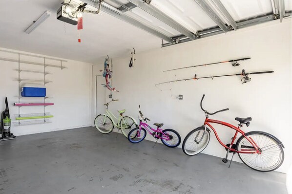 A garage with bicycles, shelves, and fishing rods.