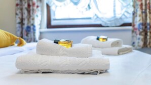 A neatly made bed with folded white towels and a bottle of lotion. - Remarkable 3-bed Apartment in London (London)