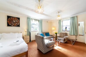 Relax in a stylishly designed room with a comfortable sofa, armchair, and neatly made bed.