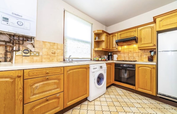 Kitchen with washing machine, stove, and window.