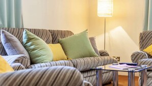 A living room with striped sofas, a standing lamp, and a small table with papers. - Remarkable 3-bed Apartment in London (London)
