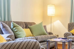 Relax in this inviting living room with a striped sofa, armchair, and floor lamp.