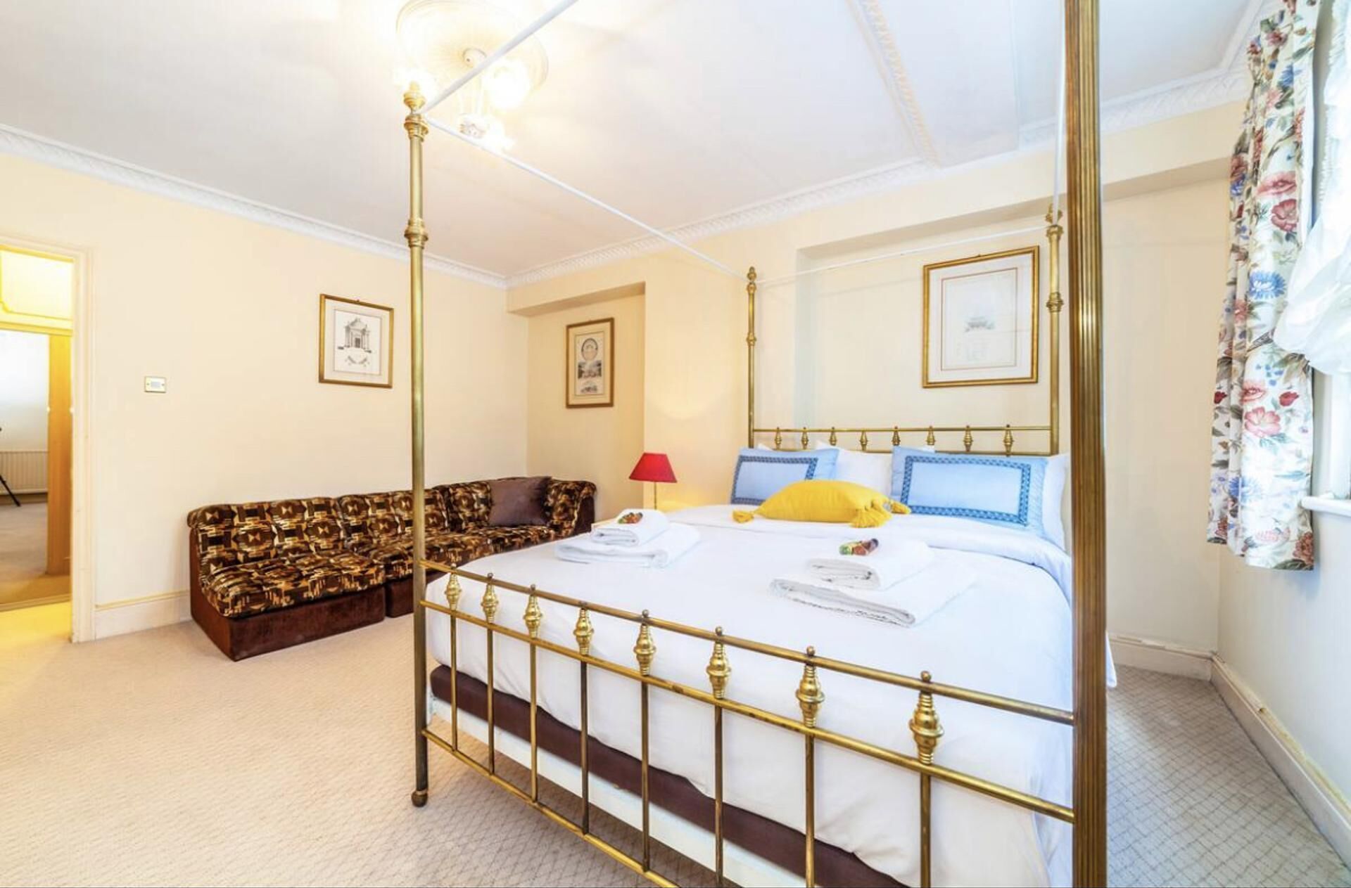 A bedroom with a four-poster bed, a sofa, and a red lamp.