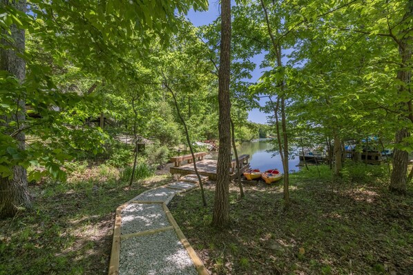 Un cadre paisible au bord du lac, avec une terrasse en bois, des bancs et des kayaks à proximité de l’eau.