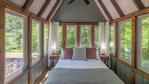Un dormitorio con una cama grande, vigas de madera y varias ventanas.