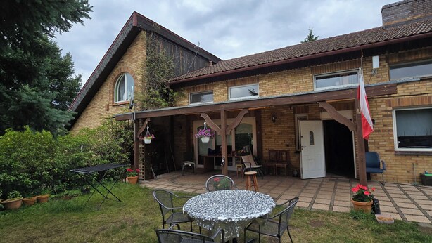 Une maison à deux étages dotée d’un patio couvert, d’une façade en briques et d’un drapeau.