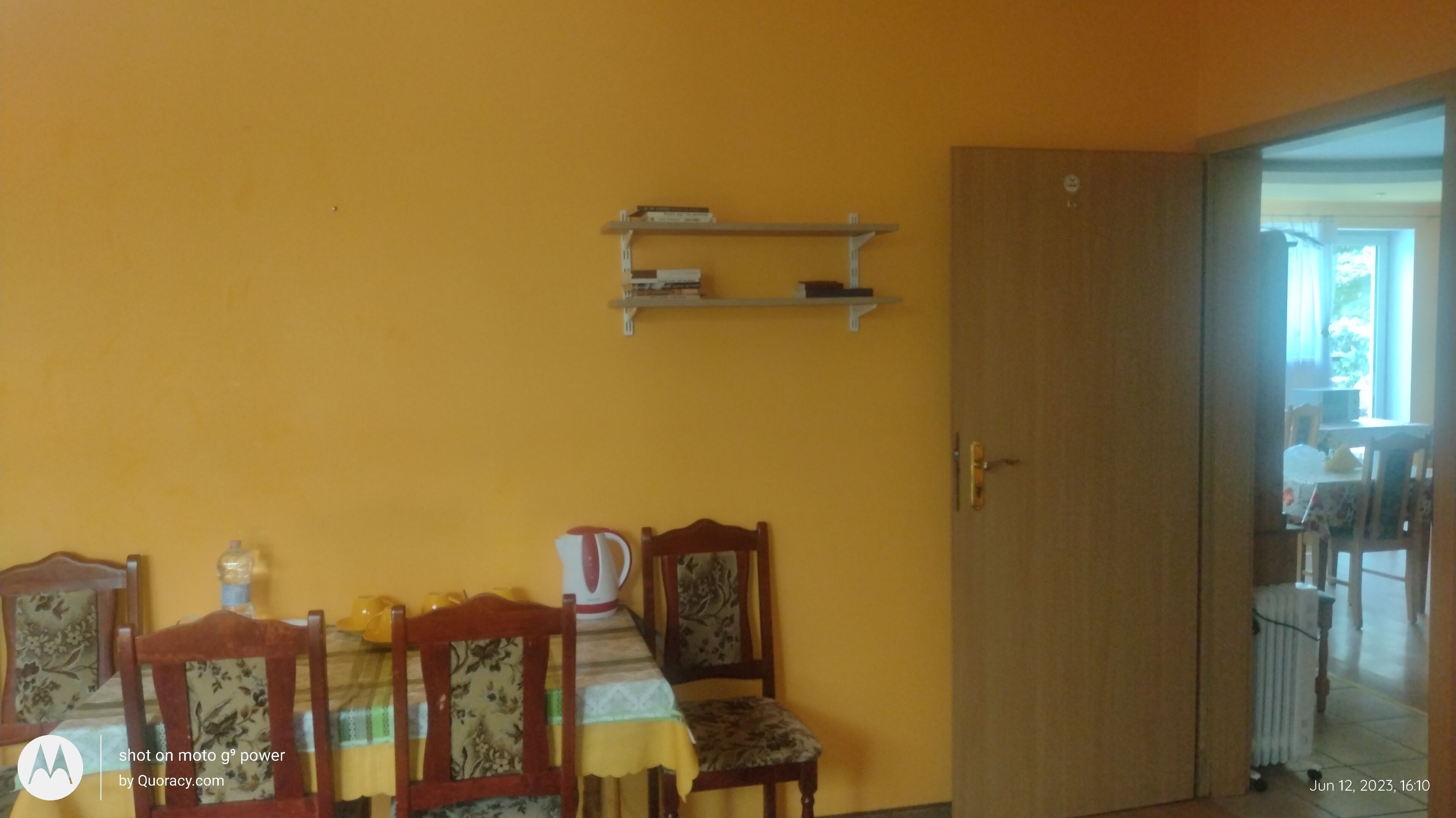 A dining area with a yellow wall, a wooden door, and a table set with chairs.