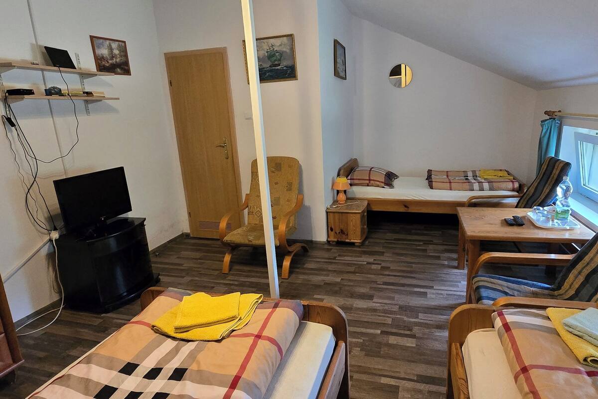 Een kleine hotelkamer met twee bedden, een bureau, een stoel, een televisie en een kledingkast.
