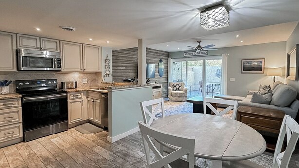 A modern kitchen with a built-in microwave, oven, and sink. There is a dining area with a round table and chairs. - Sunset Rentals | Continental Club 16 (Hilton Head Island)